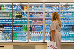 Large selection of drinking water in the supermarket refrigerator. Woman choosing drinking water in a store. Minsk, Belarus, 2022